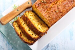 Cake à la feta, au coulis de tomates et au basilic présenté dans un plat, avec des tranches découpées