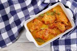 Lapin à la moutarde et à la crème présenté dans un plat posé sur un torchon rustique bleu et blanc