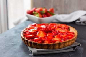 Tarte aux fraises bien brillante posée sur un torchon gris