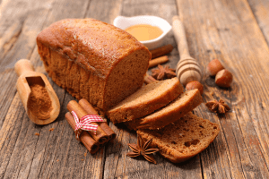 Pain d'épices maison, présenté avec des tranches coupées, et de la caneille et du miel.