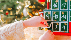 calendrier de l'avent avec des cases en bois, ouvert par une main d'enfant