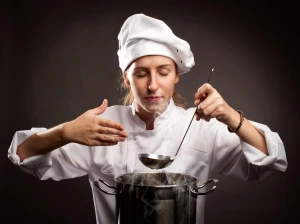 chef gastronomique à domicile, femme cheffe cuisinière qui sent une soupe fraichement préparée