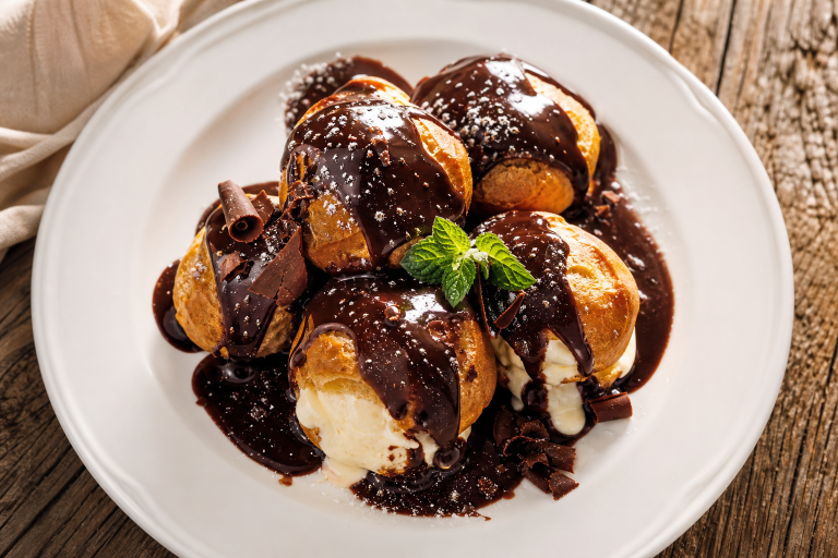 Assiette de profiteroles au chocolat, choux dorés garnis de glace à la vanille et nappés de sauce au chocolat